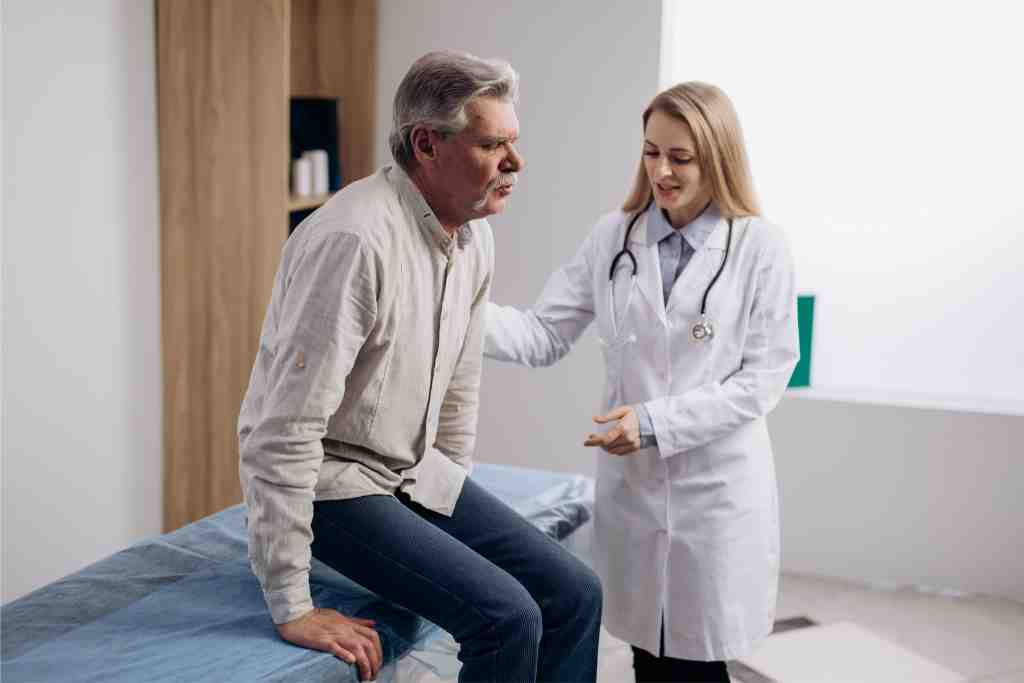 Mann in mittlerem Alter mit Gelenkschmerzen bei Ärztin